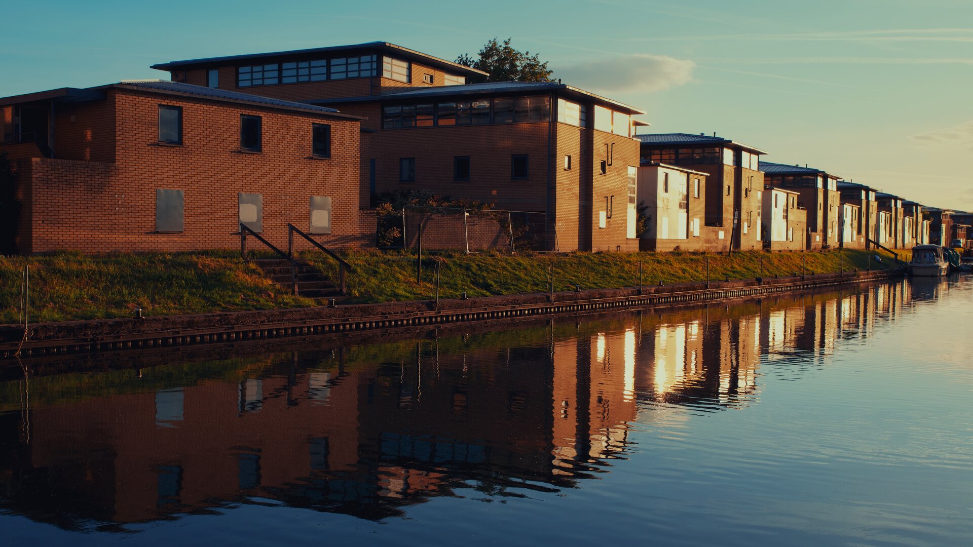 A row of canalside buildings reflected in still water at golden hour