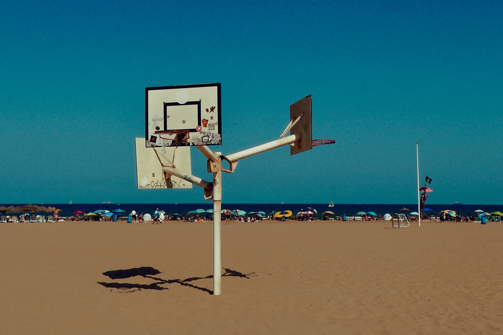 A basketball hoop on a busy beach with the sea beyond