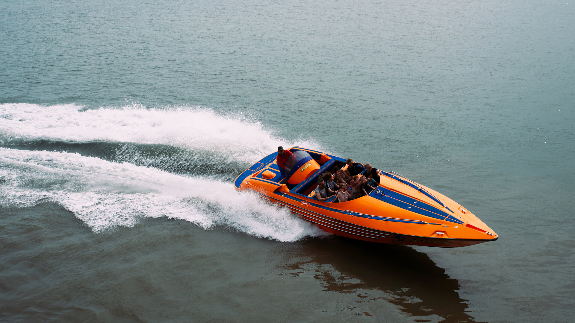 An orange speedboat throwing up spray as it banks at speed